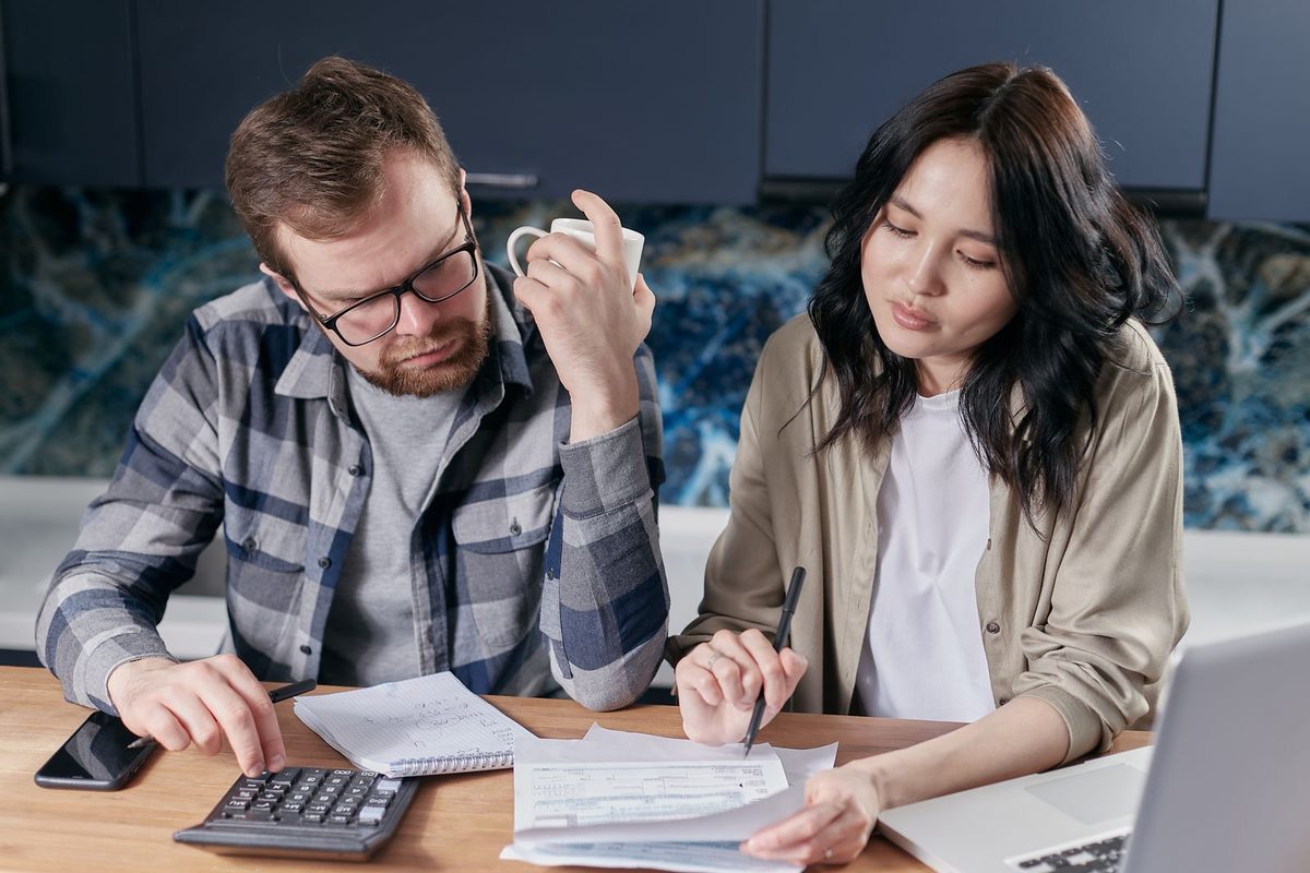 Couple faisant ses comptes, calculatrice et factures étalées
