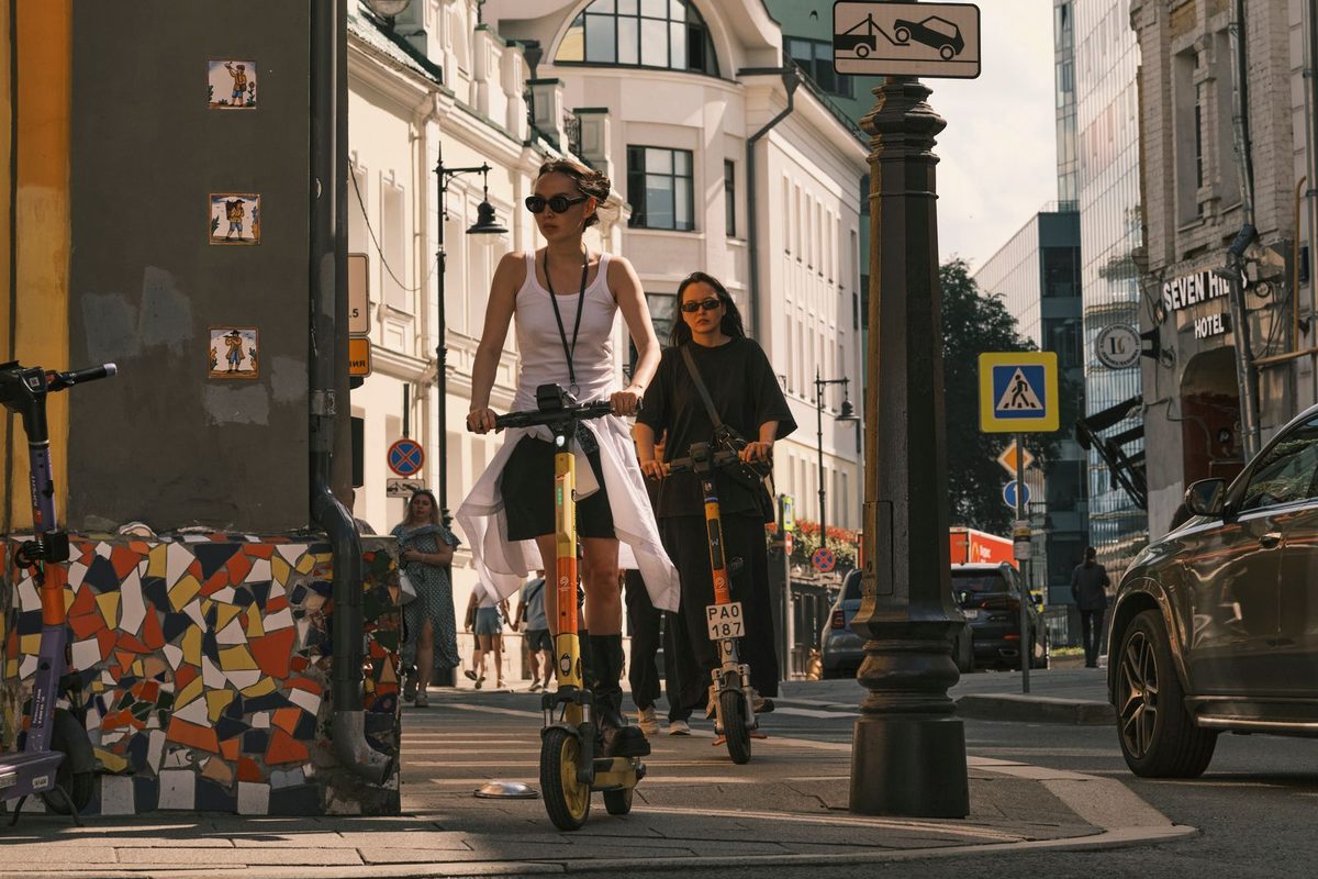 Deux personnes circulant en trottinette électrique dans une rue