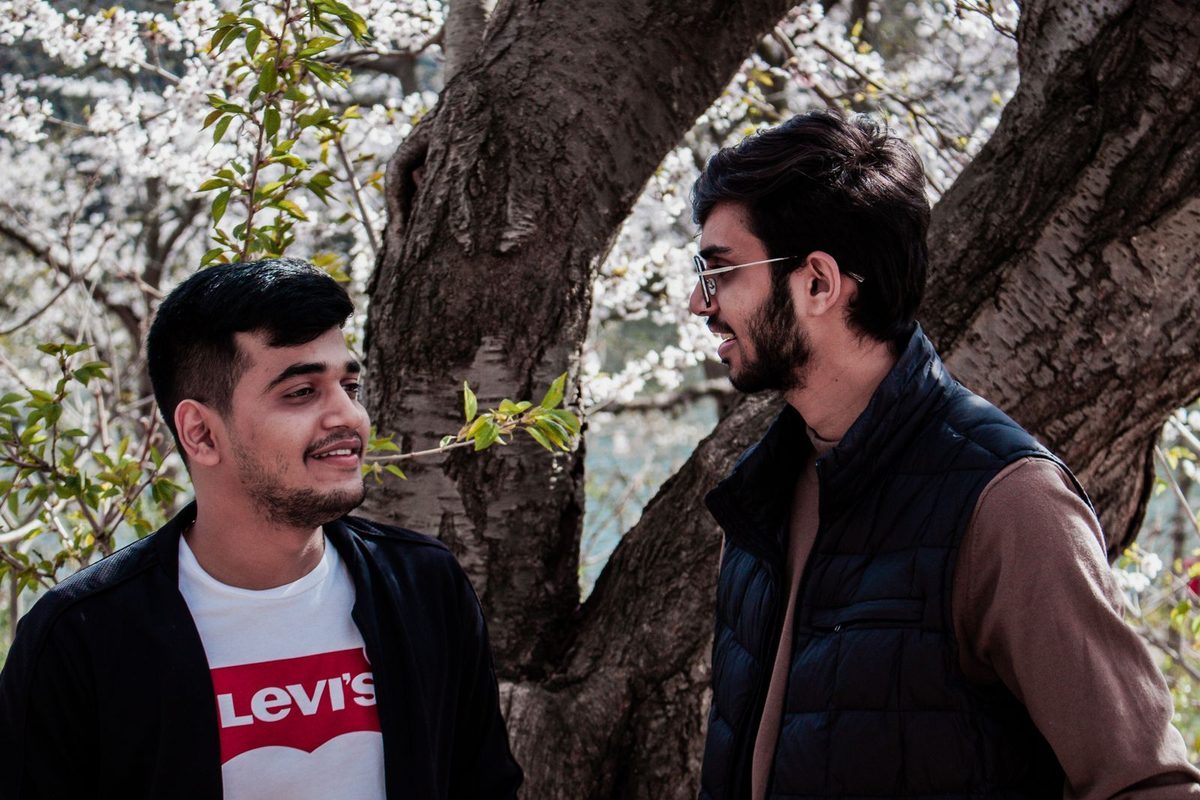 Deux amis souriant en discutant sous un arbre en fleurs
