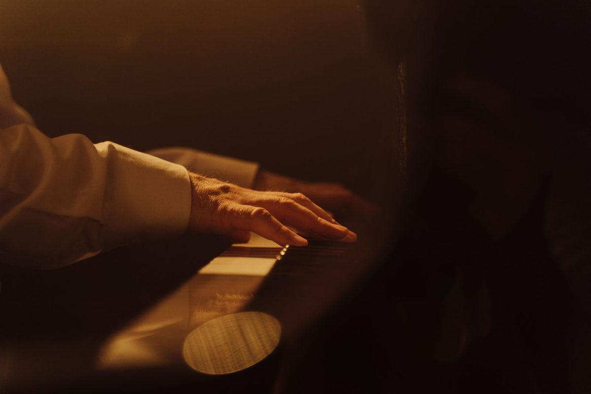 Main d'un musicien courant sur les touches d'un piano, en lumière chaude