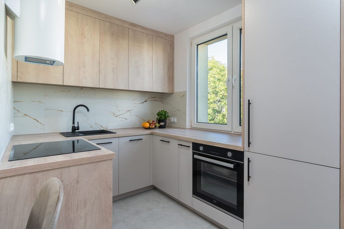 Petite cuisine en L, meubles clairs et plan de travail dégagé