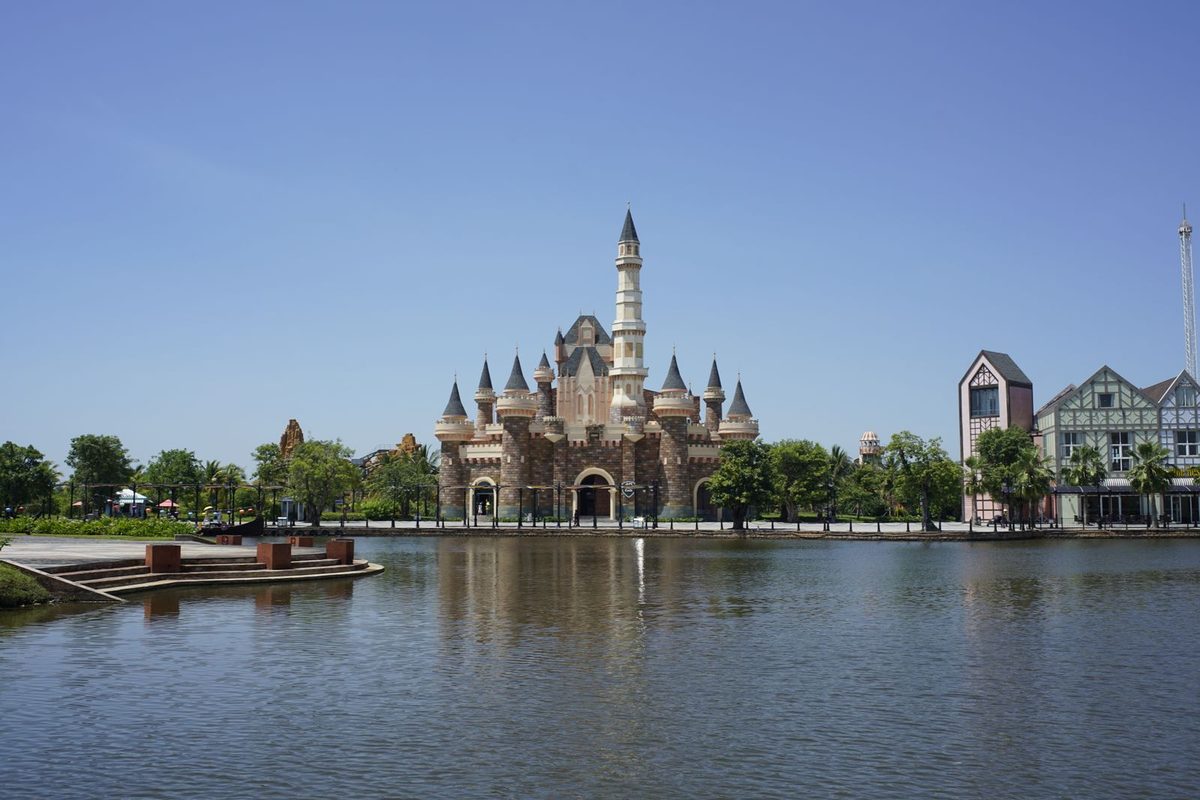 Château de parc d'attractions se reflétant dans un plan d'eau