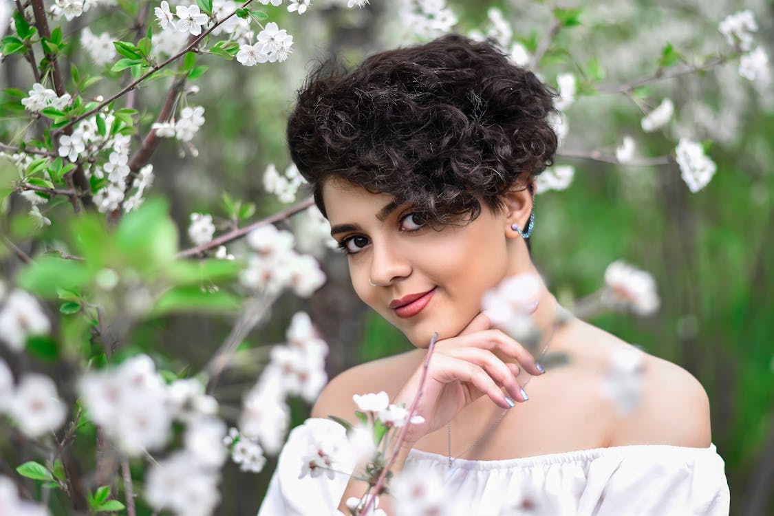 Femme aux cheveux bouclés parmi des fleurs de printemps