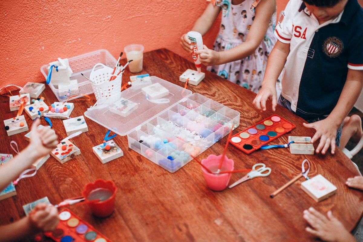 Enfants peignant à l'aquarelle autour d'une table en bois
