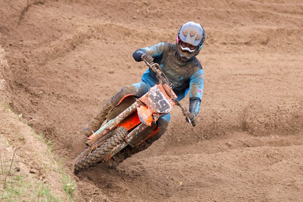 Pilote de motocross en appui dans un virage en terre