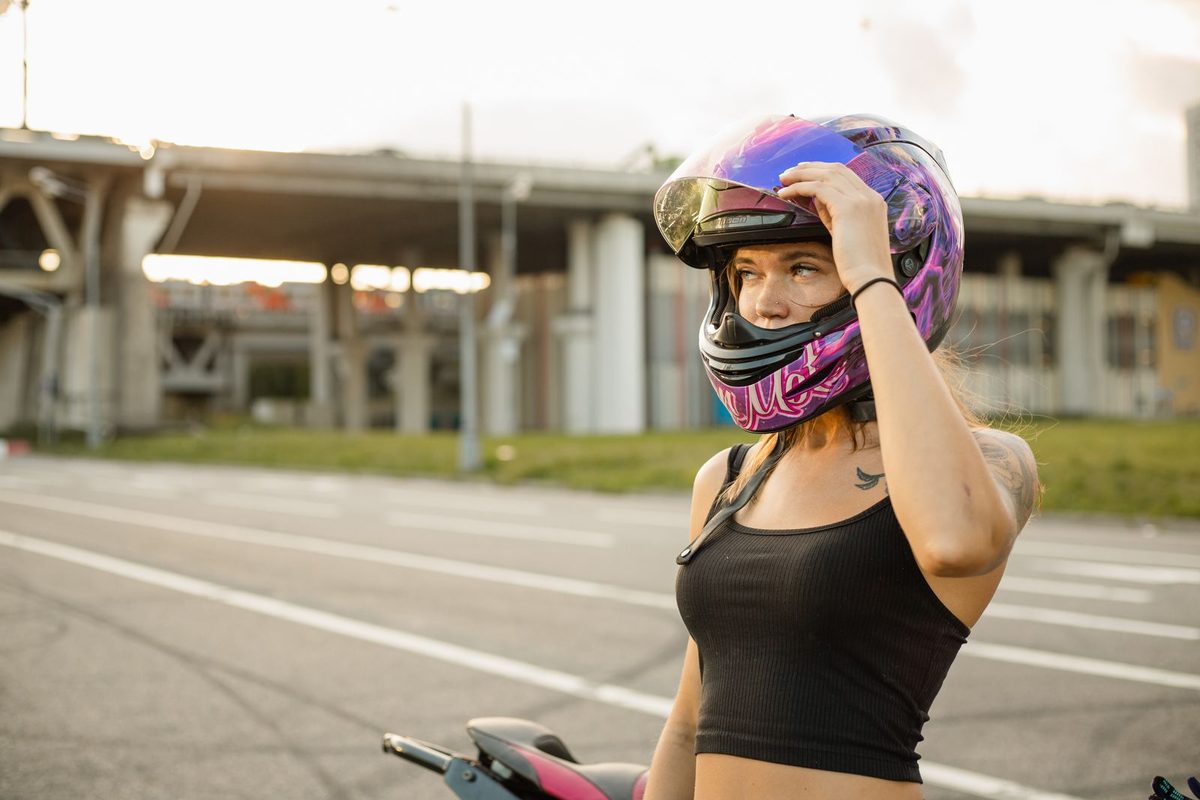 Motarde casquée à côté de sa moto dans une rue, en fin de journée