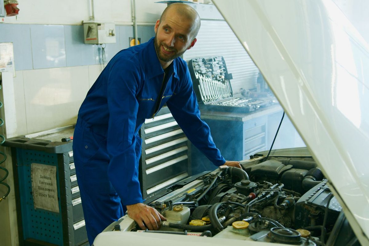 Mécanicien penché sur un moteur, capot ouvert