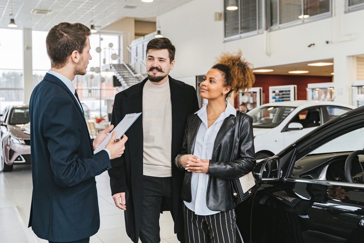 Couple discutant avec un vendeur dans une concession automobile