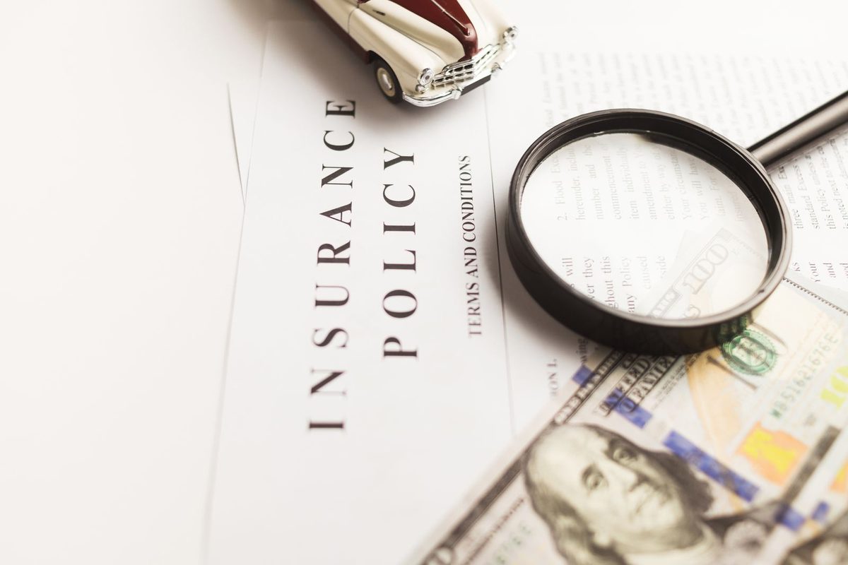 Contrat d'assurance, loupe et voiture miniature posés sur un bureau