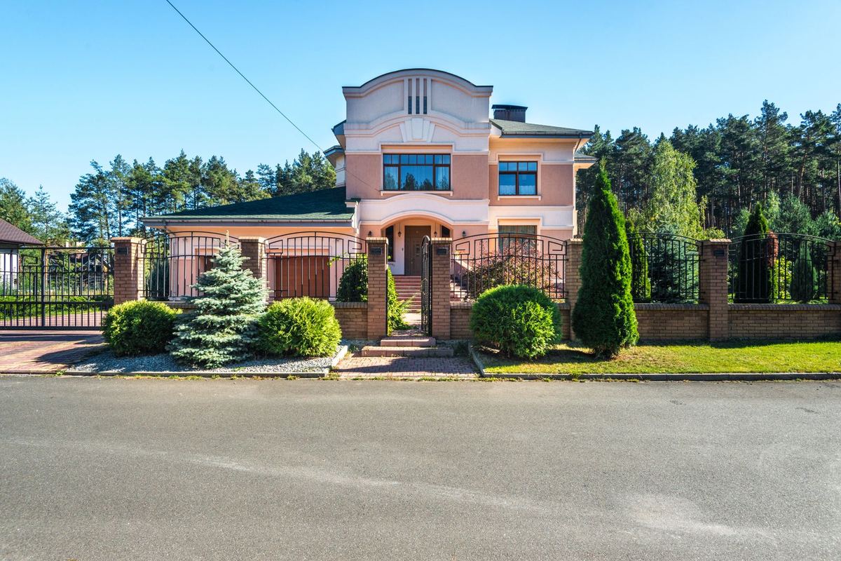Maison entourée d'une clôture et d'un portail fermé donnant sur la rue