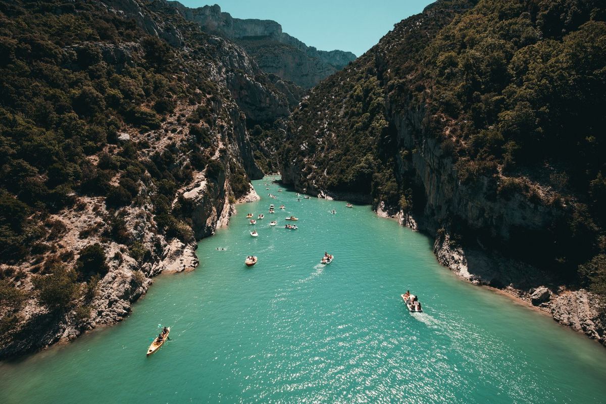 Vue aérienne de canoës sur une rivière turquoise encaissée entre de hautes falaises