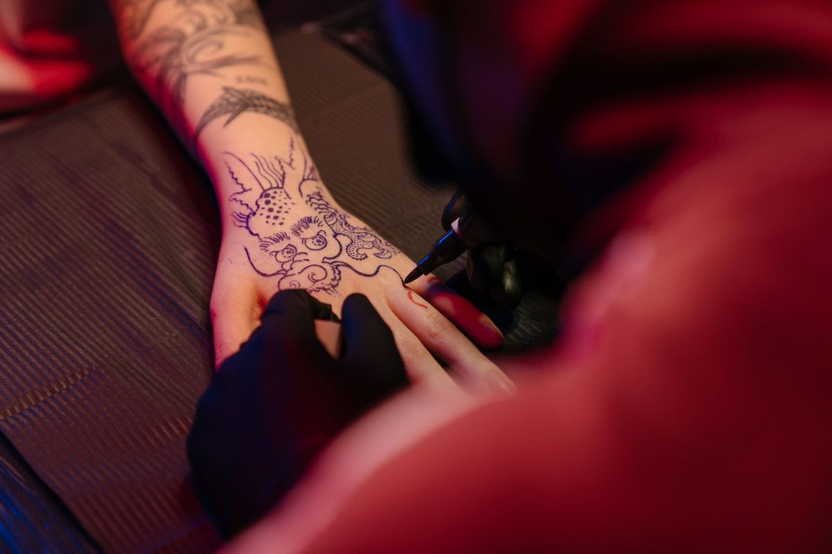 Tatoueur travaillant sur la main d'un client
