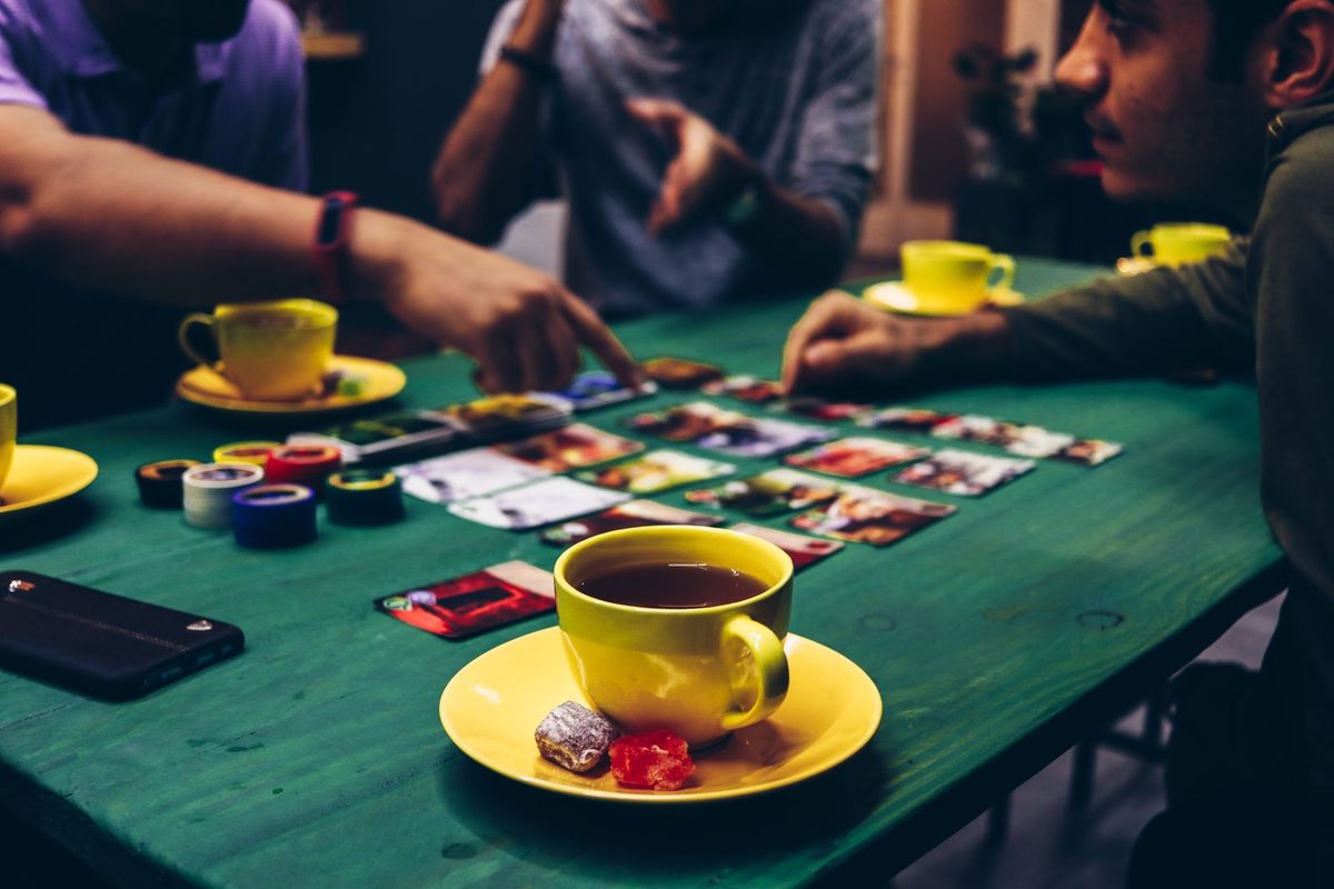 Groupe d'adultes autour d'une table de jeu, cartes et tasses de thé