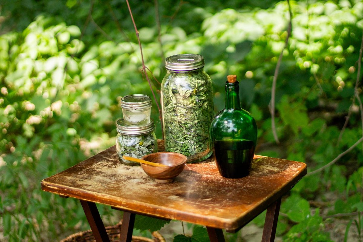 Bocaux de plantes séchées et flacon posés sur une table, en extérieur