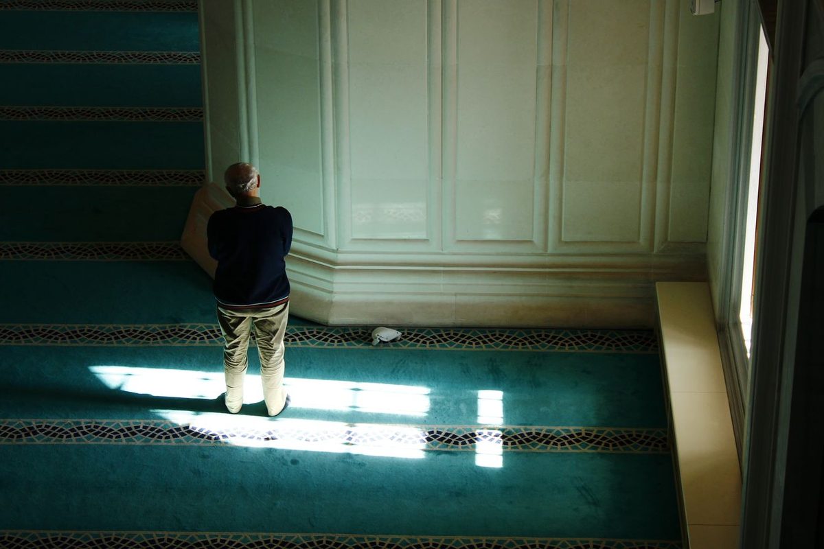 Fidèle en prière, seul, dans la lumière d'une salle de prière