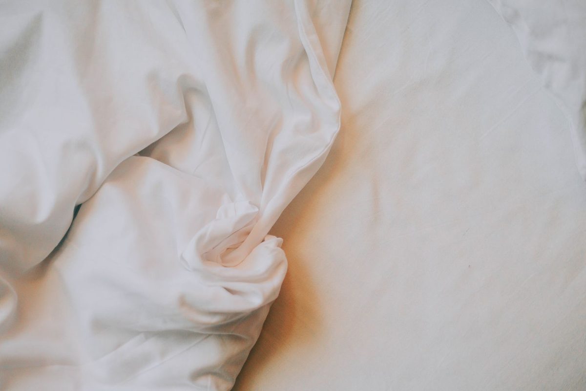 Draps blancs froissés sur un matelas, en lumière douce