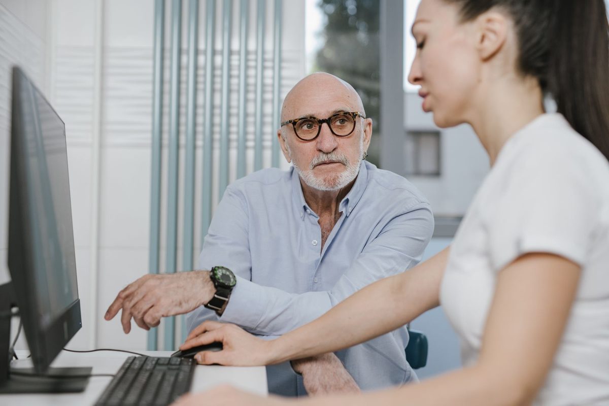 Homme senior examinant un dossier avec une professionnelle de santé