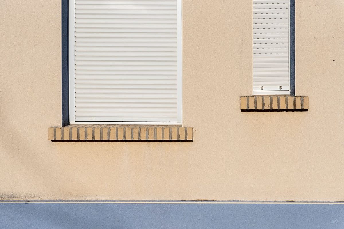 Volets roulants baissés sur la façade beige d'une maison