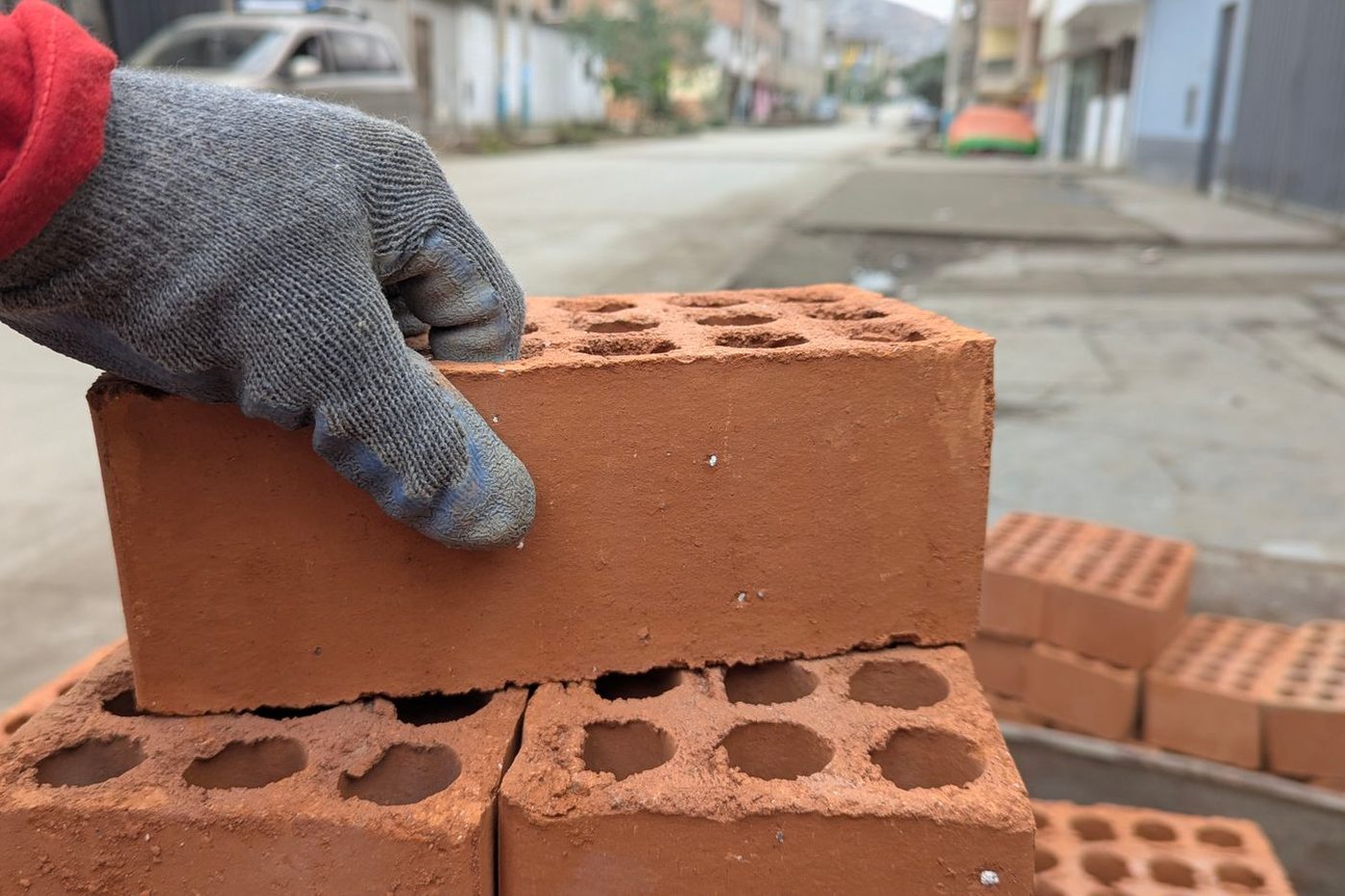 Main gantée posant une brique sur un rang de maçonnerie