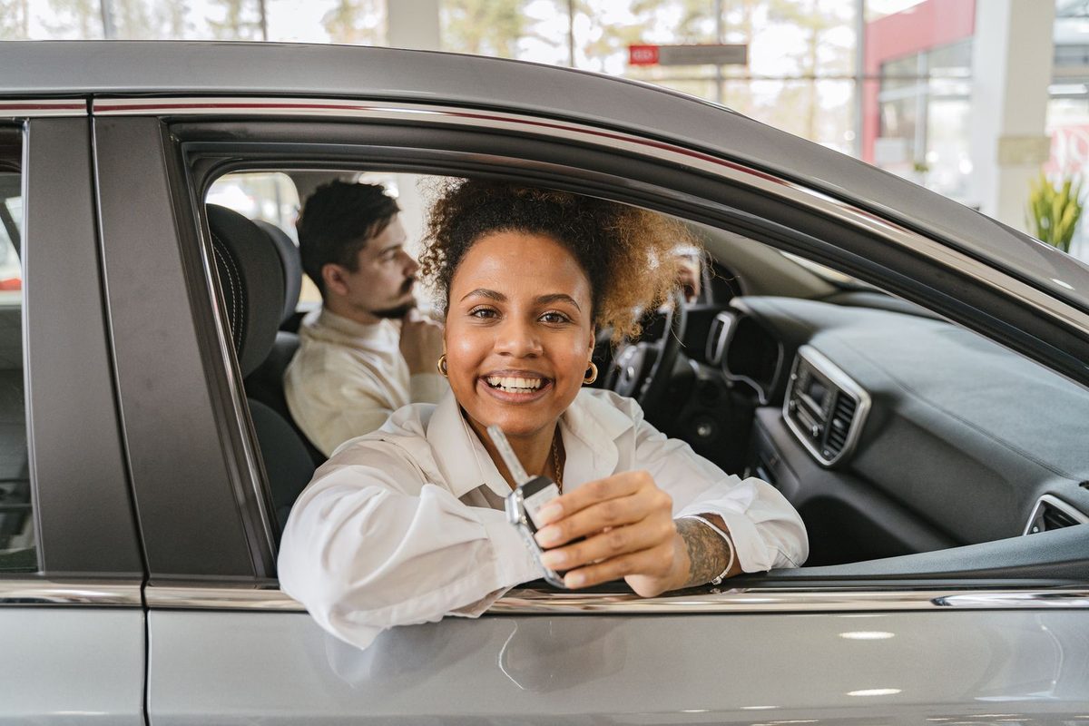 Conductrice souriante à la portière de sa nouvelle voiture
