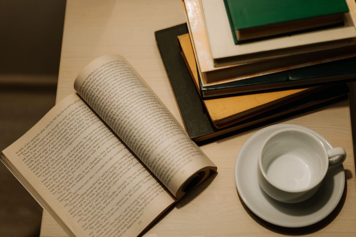 Livre ouvert posé près d'une tasse et d'une pile d'ouvrages