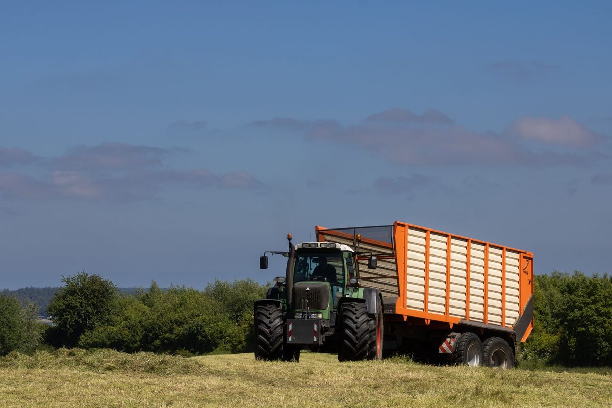 Tracteur attelé à une benne agricole dans un champ