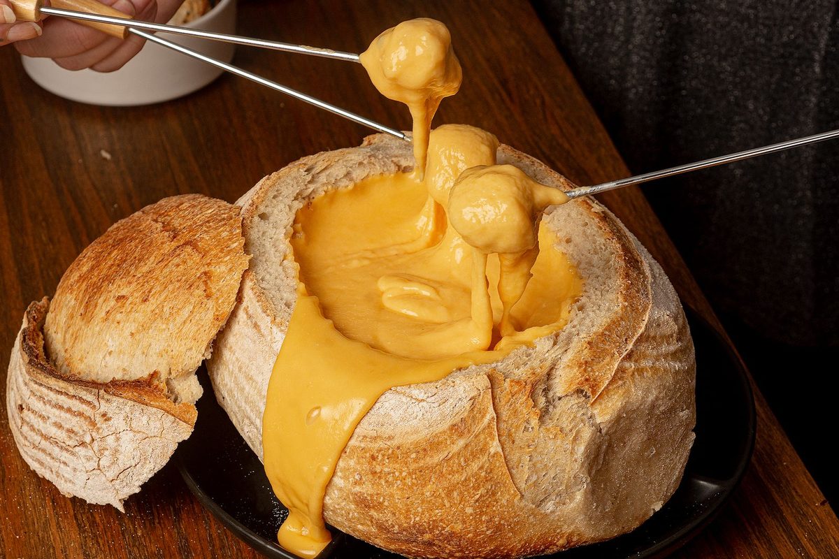 Fondue au fromage servie dans une miche de pain creusée