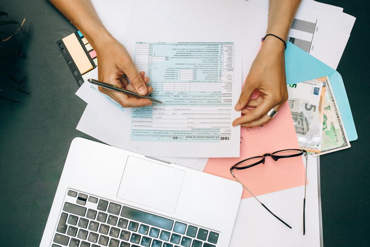 Mains remplissant un formulaire fiscal à côté d'un ordinateur portable