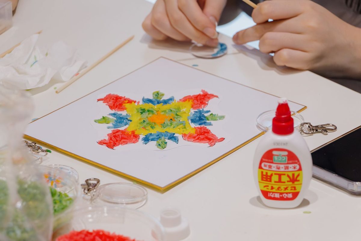 Mains posant des strass colorés sur une toile de broderie diamant