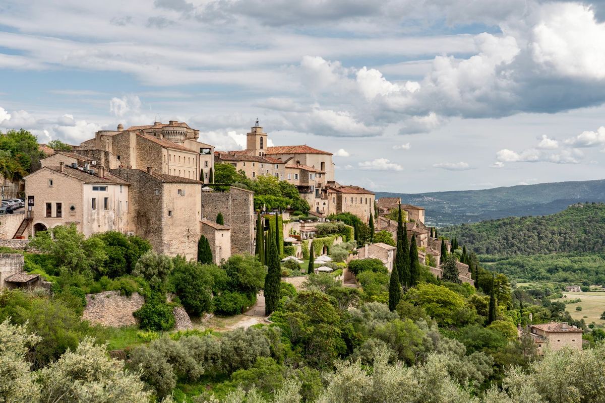 Village perché de Provence entouré d'oliviers, sous un ciel nuageux
