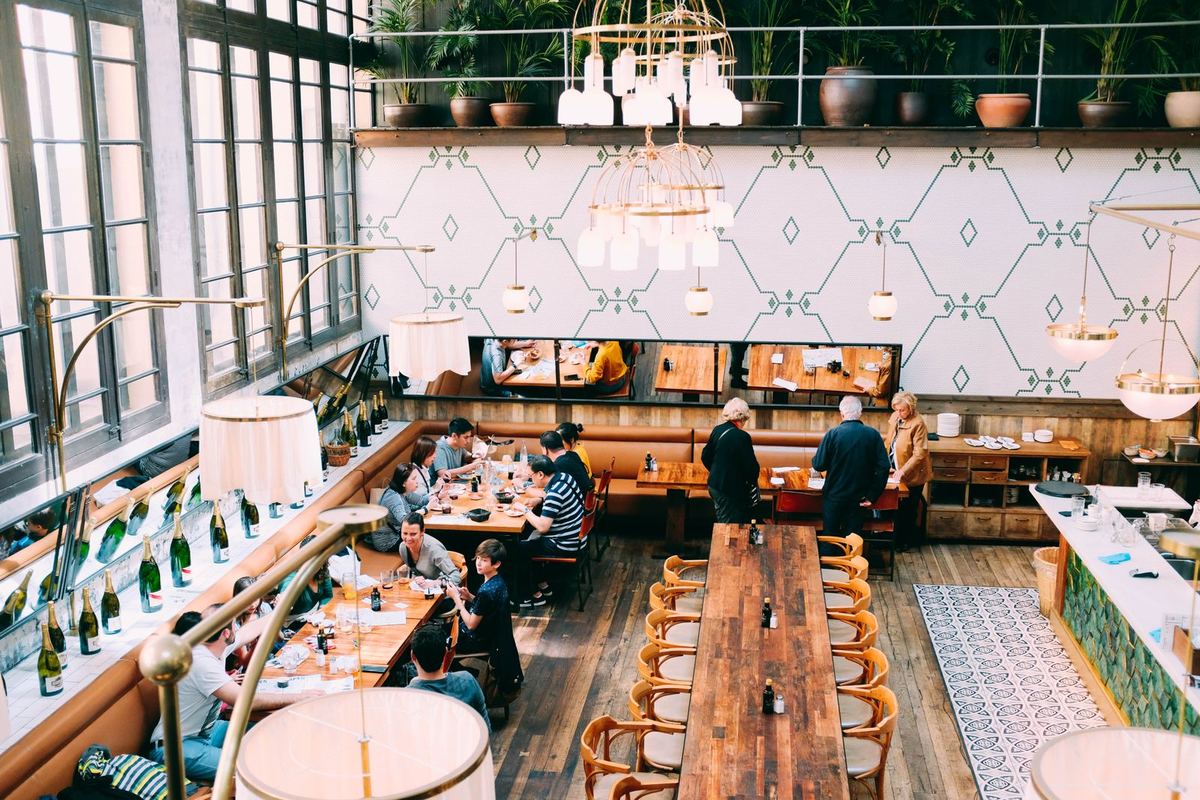 Salle de restaurant animée, longues tables en bois