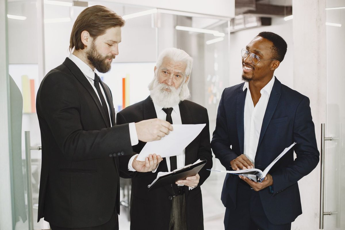Trois personnes en costume examinant des documents dans un bureau