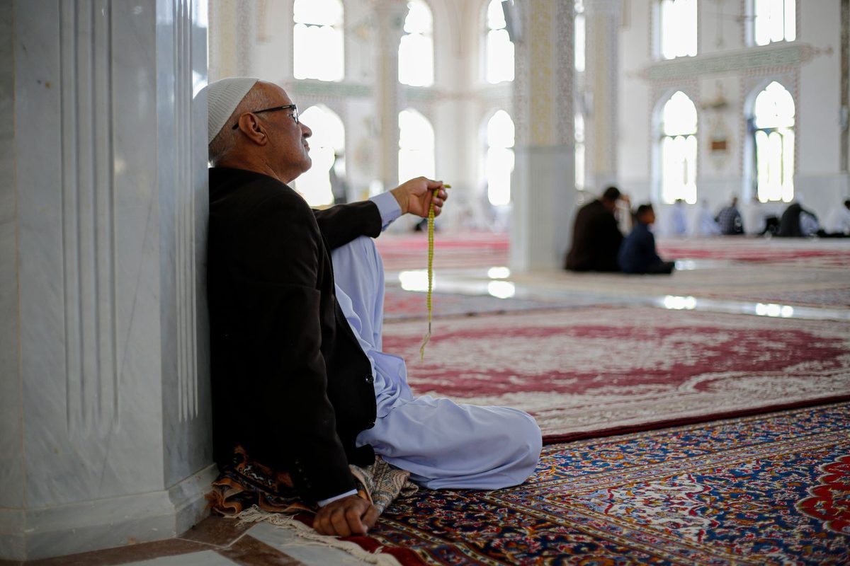 Homme en prière, chapelet à la main, dans une mosquée