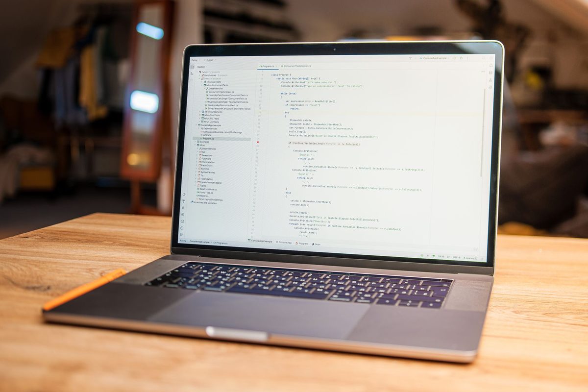 Ordinateur portable ouvert sur un éditeur de code, posé sur un bureau en bois