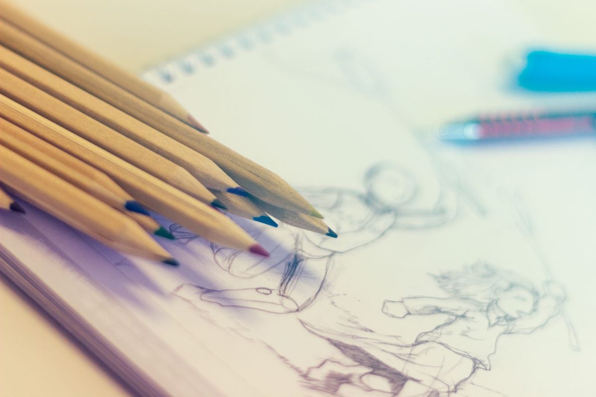 Crayons de couleur posés sur un carnet de croquis