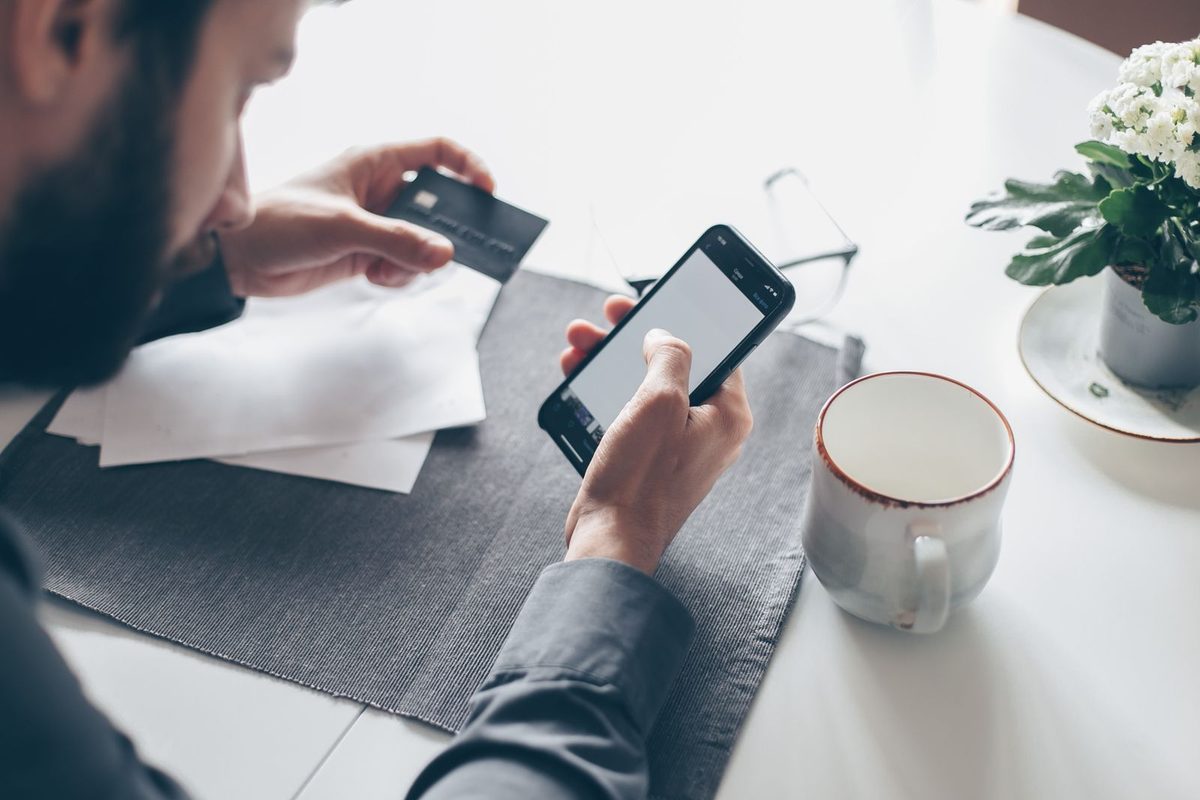 Paiement en ligne avec téléphone et carte bancaire en main