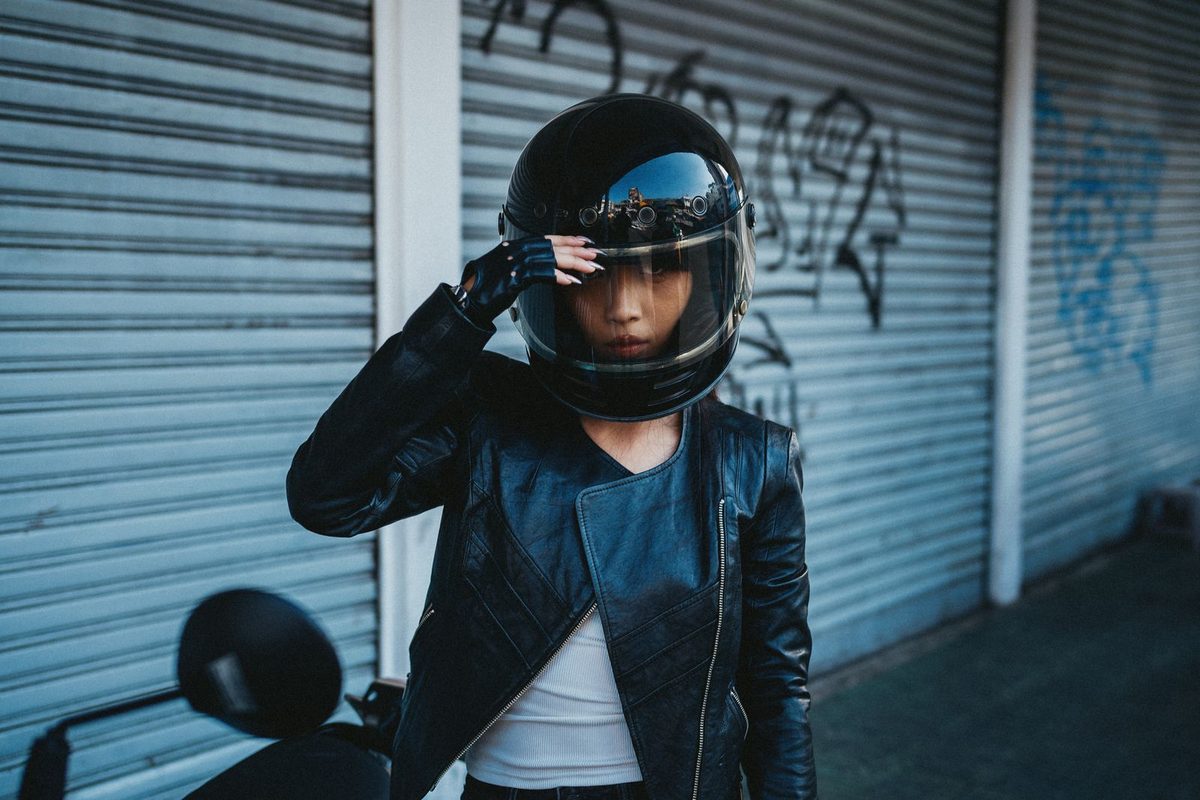 Motarde en blouson de cuir ajustant son casque intégral dans la rue