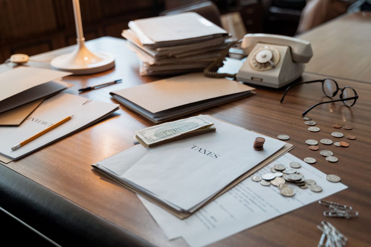 Documents fiscaux, lunettes et pièces posés sur un bureau