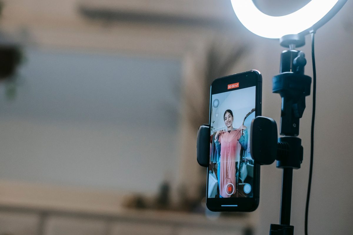 Créatrice filmant une vidéo au smartphone, éclairée par un anneau lumineux