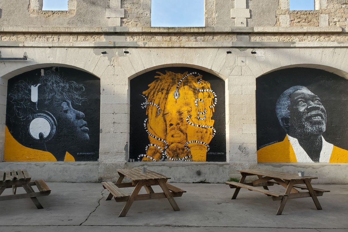 Fresques murales peintes sur un mur de pierre, devant des tables de pique-nique