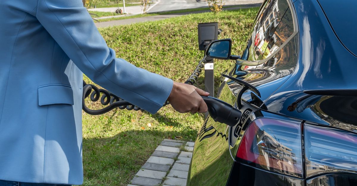 Personne branchant une voiture électrique à une borne de recharge