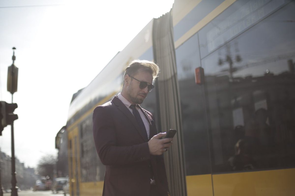 Homme consultant son smartphone dans la rue devant un tramway