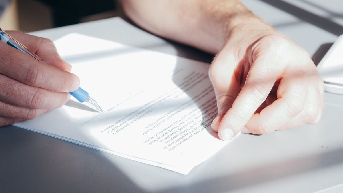 Personne rédigeant et signant un document administratif au stylo