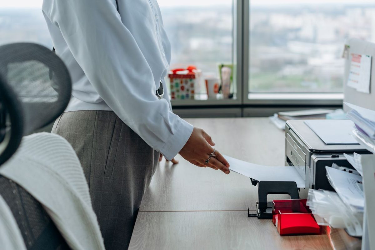 Employée récupérant un document sortant d'une imprimante de bureau