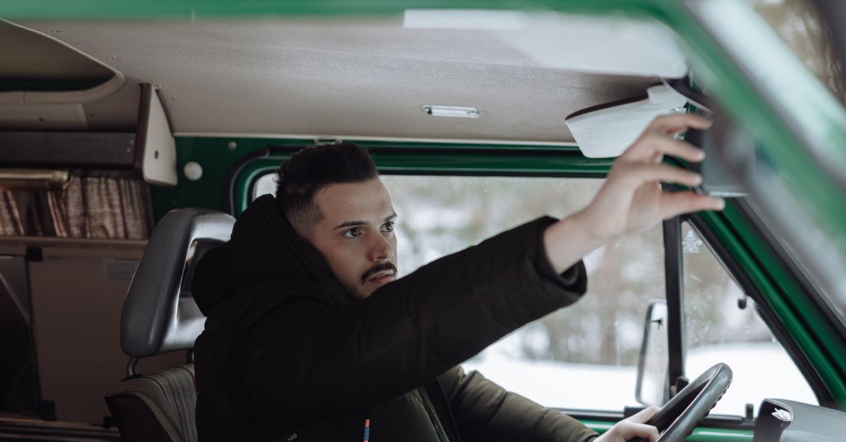 Conducteur réglant son rétroviseur
