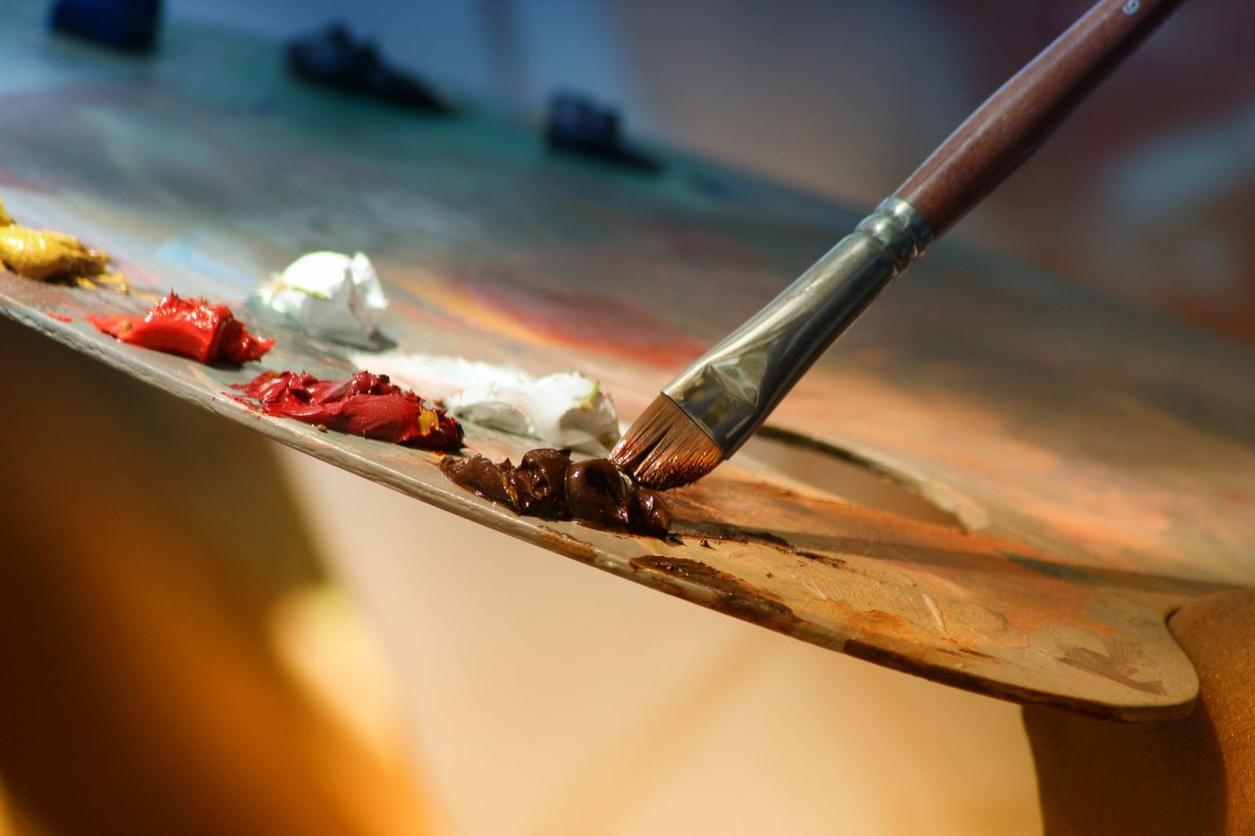 Pinceau posant de la peinture sur une palette chargée de couleurs chaudes