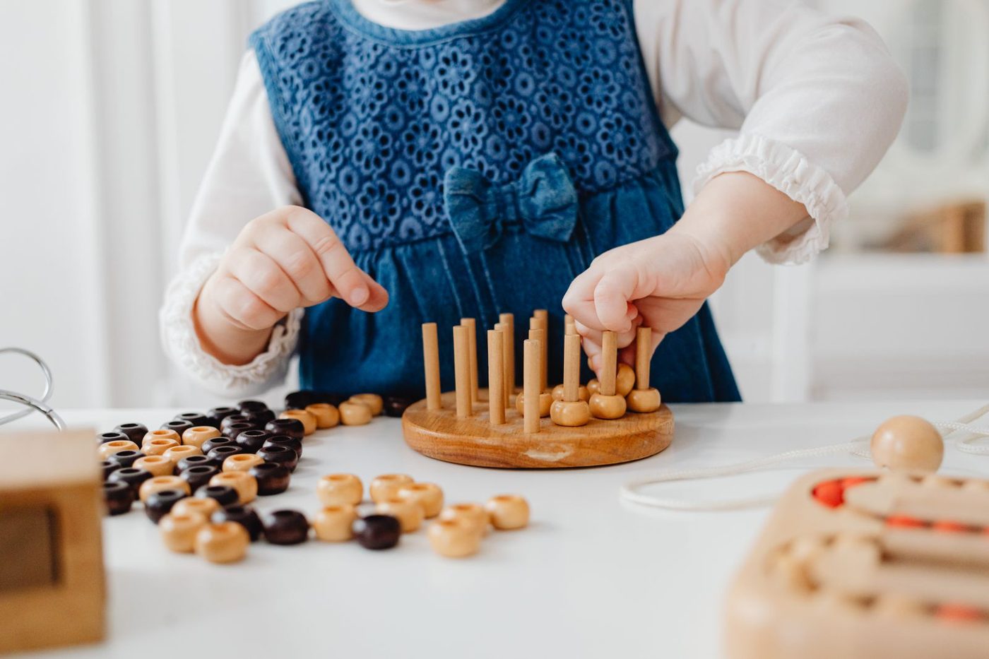 Mains d'enfant manipulant un matériel Montessori en bois sur une table
