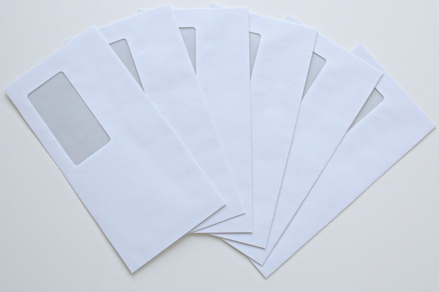 Enveloppes blanches à fenêtre disposées en éventail sur un plan clair