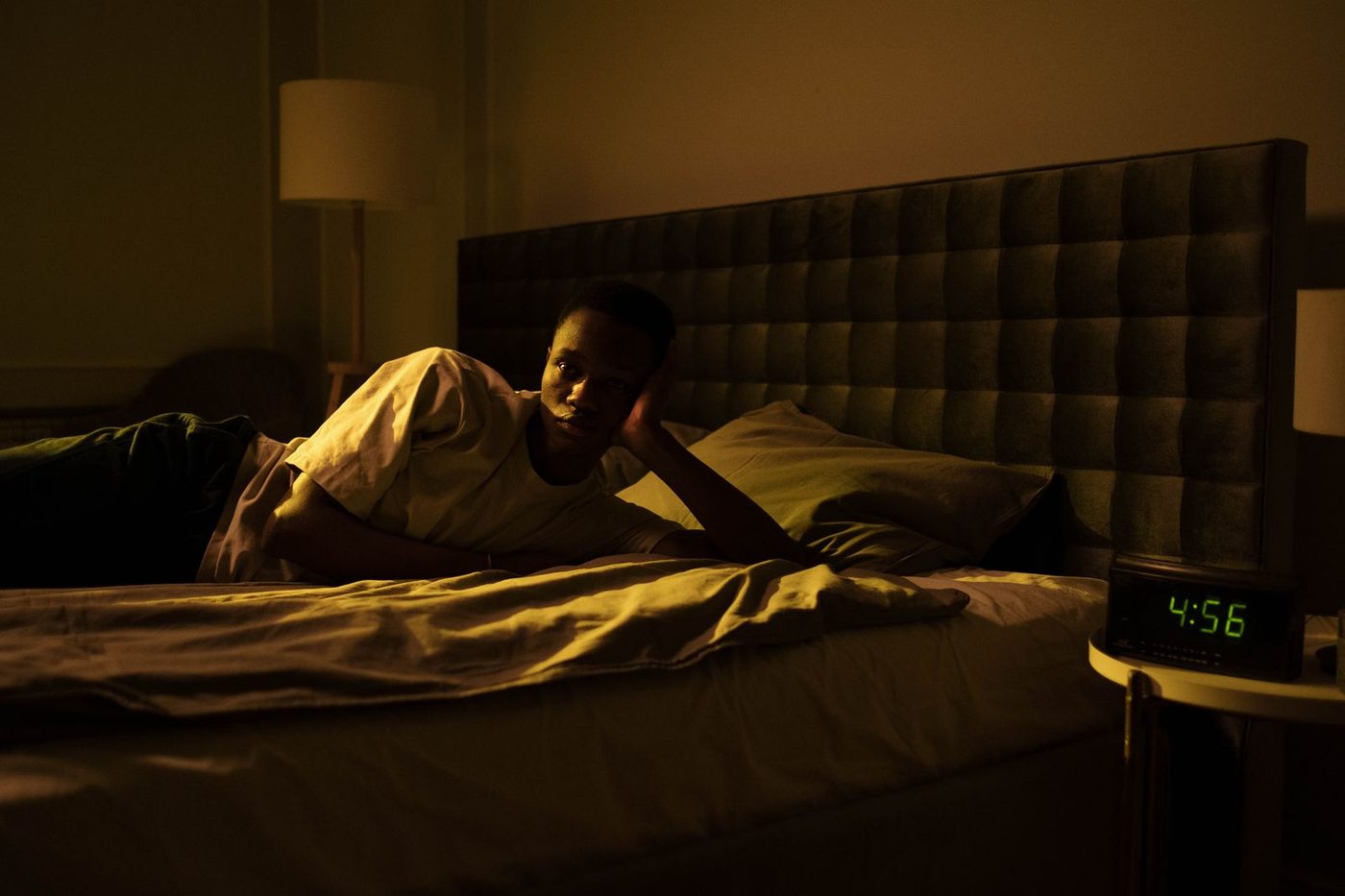 Personne éveillée dans son lit la nuit, un réveil numérique allumé à côté