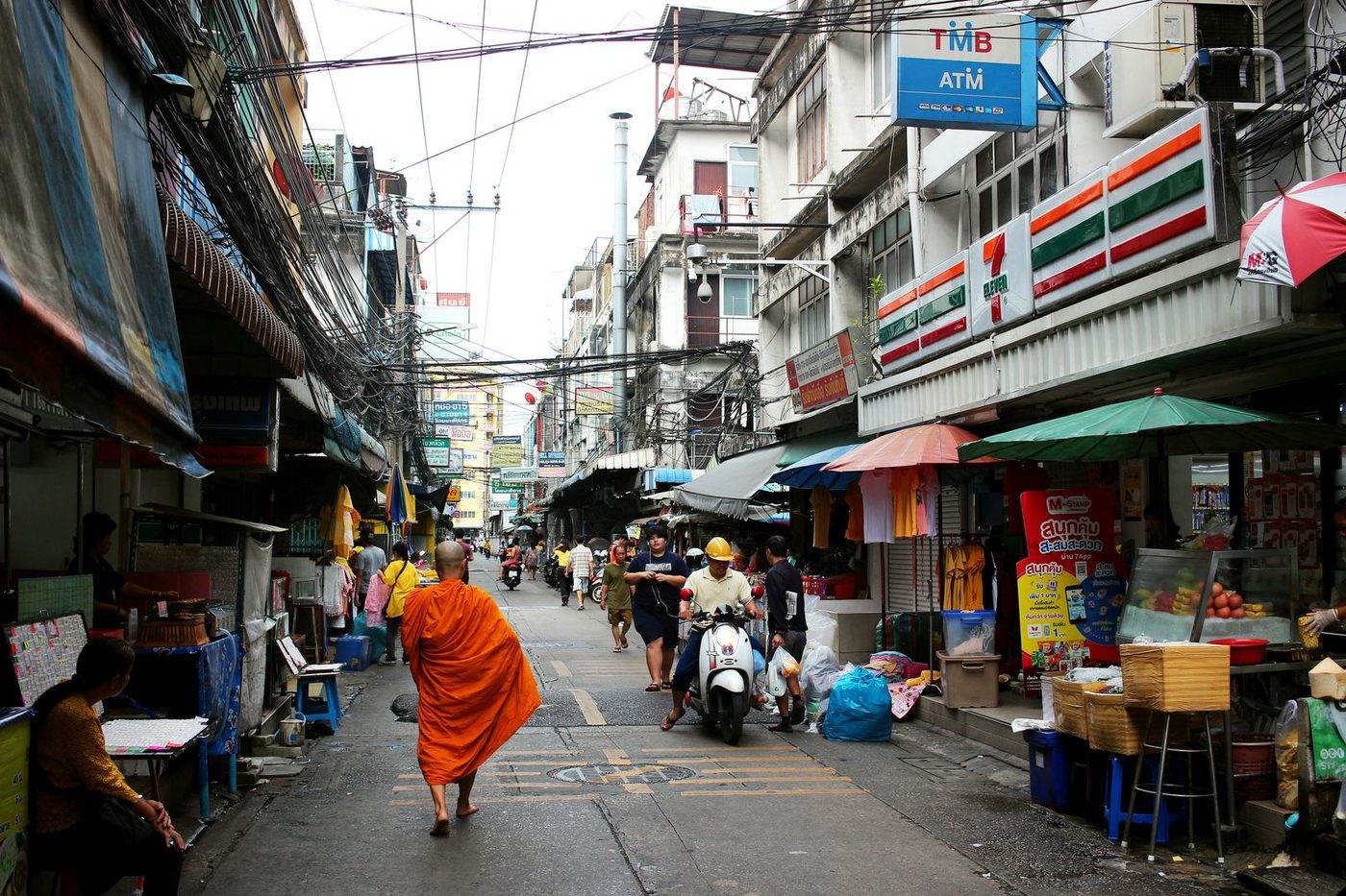 Rue commerçante de Bangkok avec échoppes et passants en fin de journée
